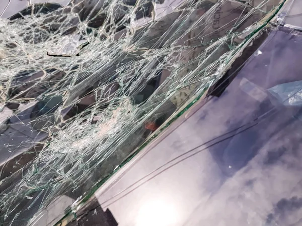 Broken windshield of abandoned and destroyed car, with broken glass.