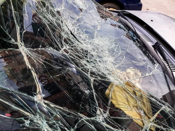 Broken windshield of abandoned and destroyed car, with broken glass.