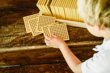 Montessori sınıfta ahşap arka plan üzerinde sayım küpleri manipüle çocuğun elleri