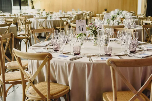 Tables and wooden chairs arranged and decorated in a wedding hall of a hotel