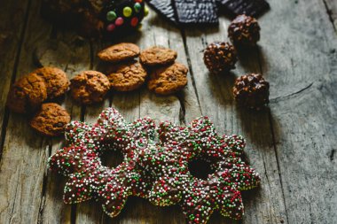 Güzel bileşimi sıcak ışık ile Noel tatlılar ve çikolata kurabiye, rustik ahşap bir masa üzerinde düzenlenen festival arka plan