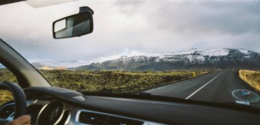 Macera seyahat dağlarda bulutlar ve kar ile yolda bir araba sahnesi.