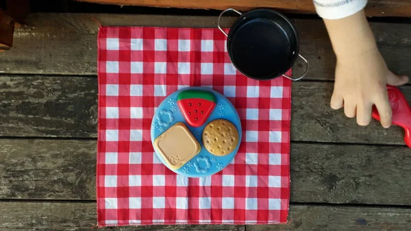 Child's hands playing a picnic with plastic food.