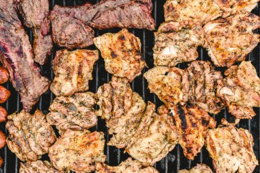 Yukarıda da görüleceği bir barbekü üzerinde sosis, domuz ve tavuk kavrulmuş.