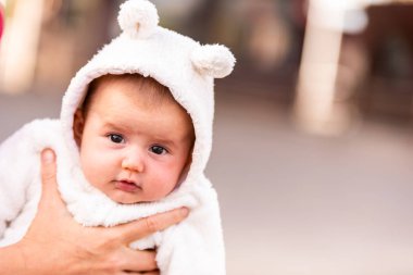 Kulaklı bir kap giymiş kız bebek gülümseyen yüzünü.