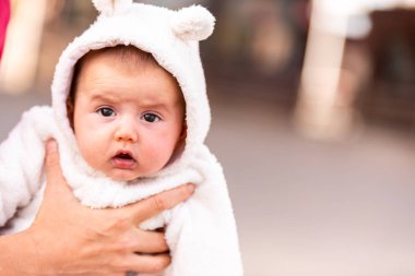 Kulaklı bir kap giymiş kız bebek gülümseyen yüzünü.