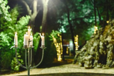 Candles lit to illuminate a garden during a dinner at night. clipart