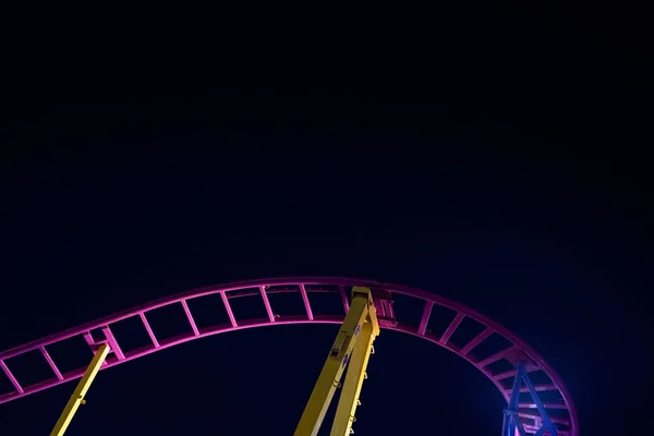 Rails of a roller coaster, blue night sky background.