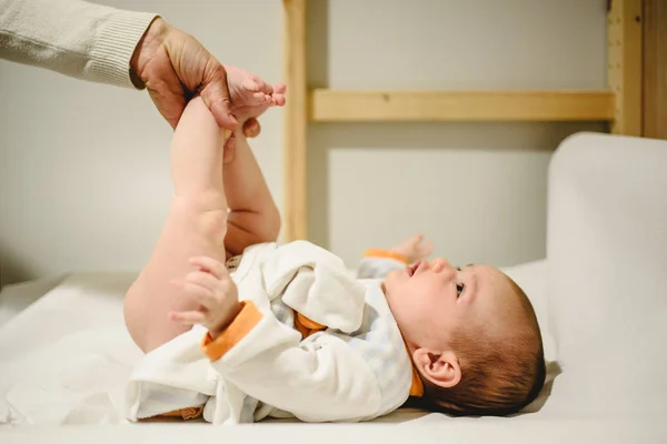 母亲给婴儿换尿布 抬起小腿 — 图库照片