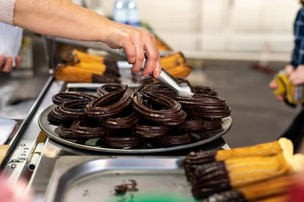 Fried dough, traditional Spanish breakfast churros bathed in chocolate, delivered by a saleswoman to a client.