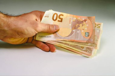 Servet bir iş göstermek için 50 euro faturaları yığını tutan adam el.