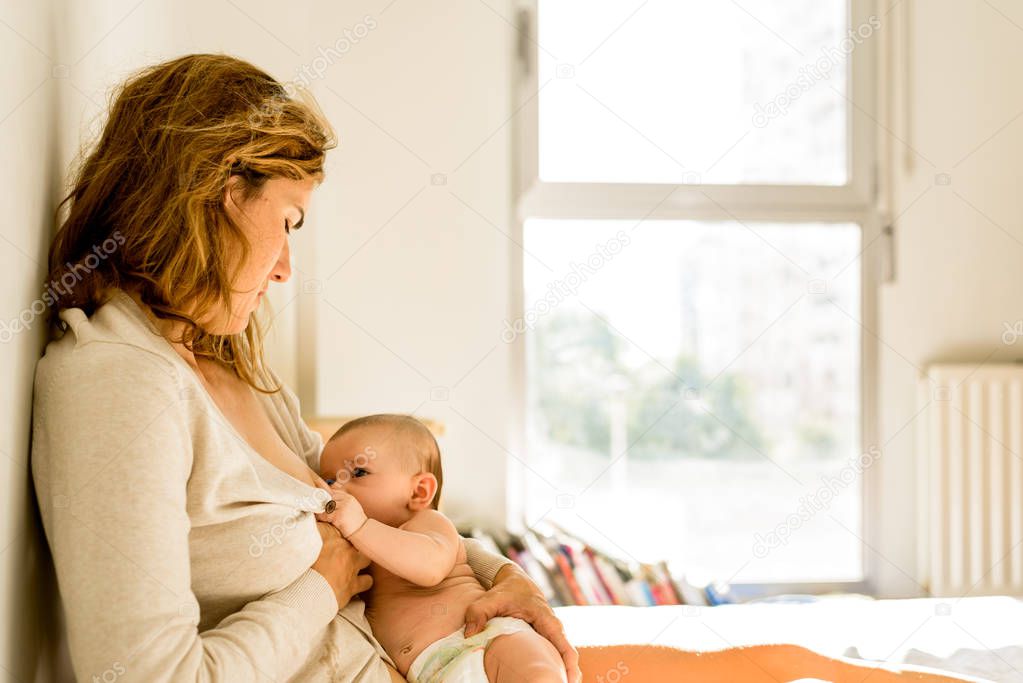 Baby breastfed by his mother in bed quiet in the morning, healthy motherhood concept.