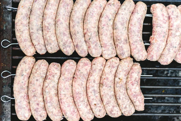Birçok beyaz sosis mangal kömür ile kızartma için üst üste.
