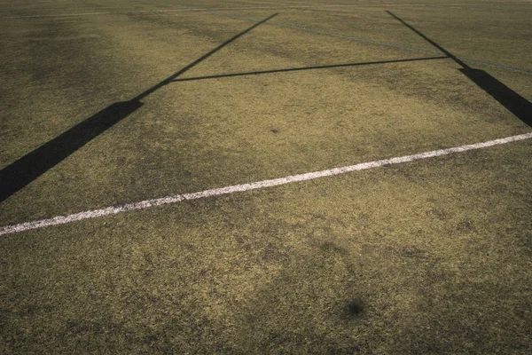 Background of a rugby goal casting shadows on the field.