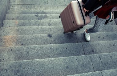 Bir metro merdivenleri tırmanmaya kadın arabası bavul sürükleme.