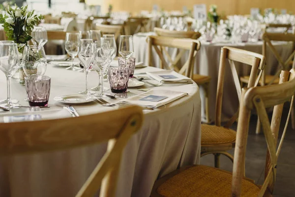 Tables and wooden chairs arranged and decorated in a wedding hall of a hotel