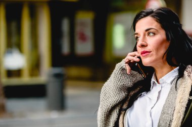 Orta yaşlı kadın sokakta onu cep telefonuyla bir aramayı cevaplama.