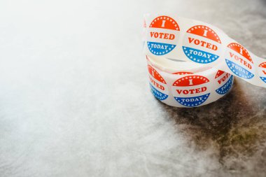 Roll of I voted circular stickers on a gray background for the November elections in the United States. clipart