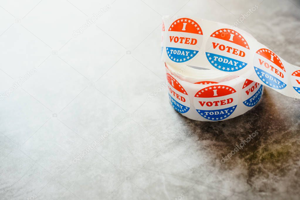 Roll of I voted circular stickers on a gray background for the November elections in the United States.