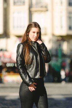 Siyah deri giysili genç kadın manken gibi poz giyinmiş.