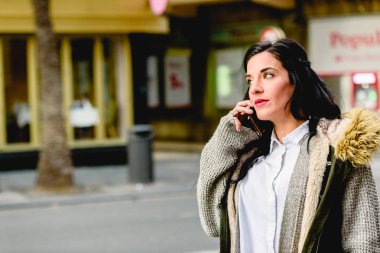 Orta yaşlı kadın sokakta onu cep telefonuyla bir aramayı cevaplama.