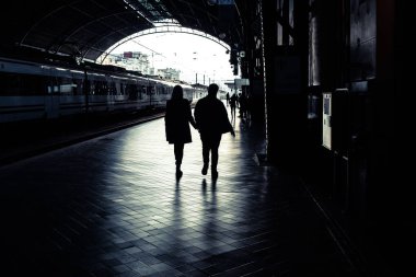 Yolcular bir tren istasyonunda silüeti.