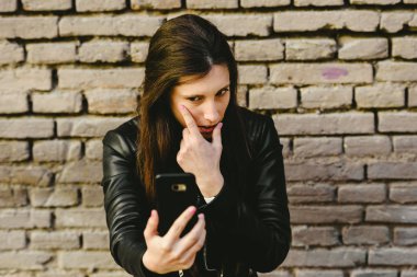 Cep telefonu ekran yüzü ve o gets çok sevgilisi ile bir tarih için makyaj ve Kaldır sivilce koymak için bir ayna olarak kullanan genç kız.