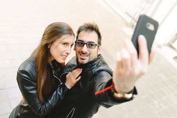 Young couple in love making a selfie on the street posing as amateur models.