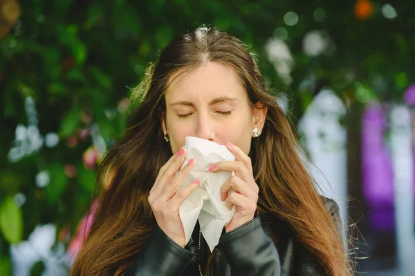 Young millennial sick woman sneeze holding tissue handkerchief and blowing wiping her running nose.