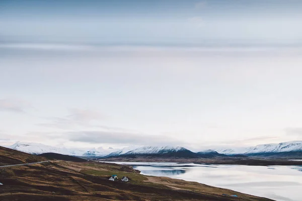 村庄与农场在冰岛的山的农村地区 以雪山为背景 — 图库照片