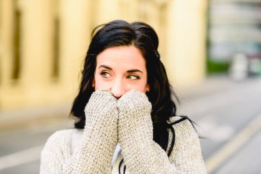 Ağzını elleriyle kapsayan sürpriz ifade ile güzel gözlü güzel esmer kadın.