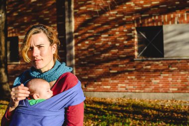 Güvenli bir şekilde güneşin bir yürüyüş sırasında bir eşarp yeni doğan bebeğini taşıyan kadın anne.