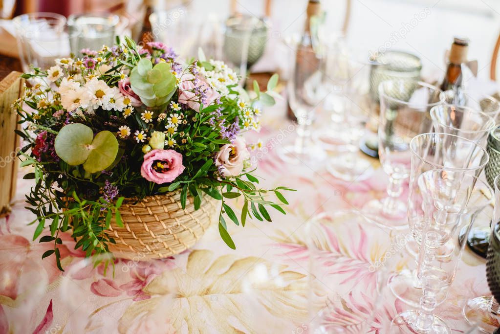Flowers decorating the centerpieces with luxury cutlery on the tables of a wedding hall.