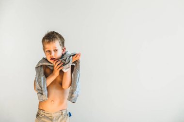 Child trying to take off his shirt and undress on his own. clipart