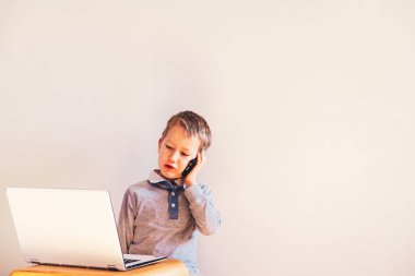 Genç çocuk cep telefonu üzerinde iş yapmak konuşurken bir dizüstü bilgisayar kullanarak.