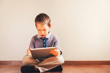 Onun elinde bir dijital tablet ile katta oturan çocuk okulda eğitim için kullanma.