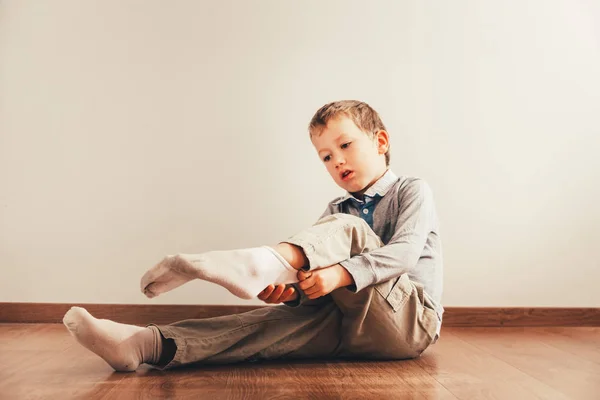 Niño Sentado Suelo Poniéndose Los Calcetines Con Una Expresión Esfuerzo —  Fotos de Stock