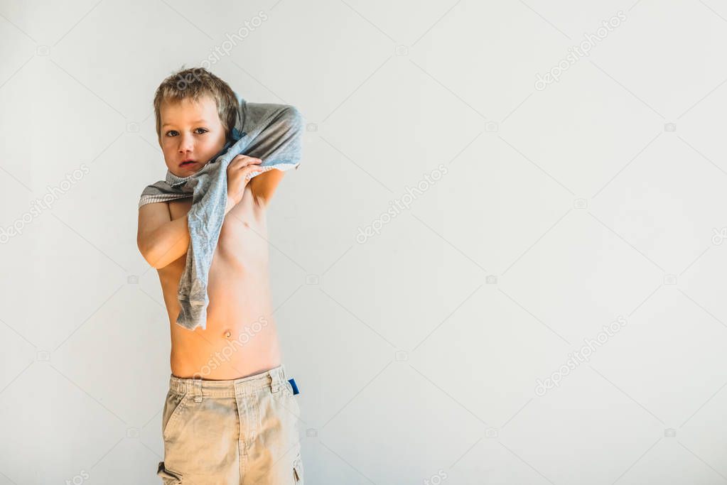 Child trying to take off his shirt and undress on his own.