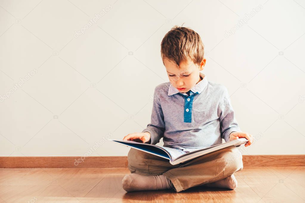 Portrait of boy interested in reading a book.