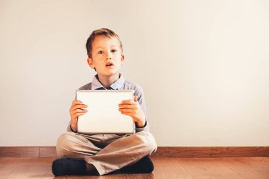 Onun elinde USI dijital tablet ile katta oturan çocuk