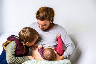 Mom breastfeeding her two sons in tandem, the two brothers share clipart