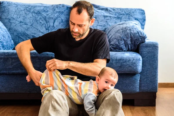 Father trying to wear his baby daughter's pajamas. — Stock Photo, Image