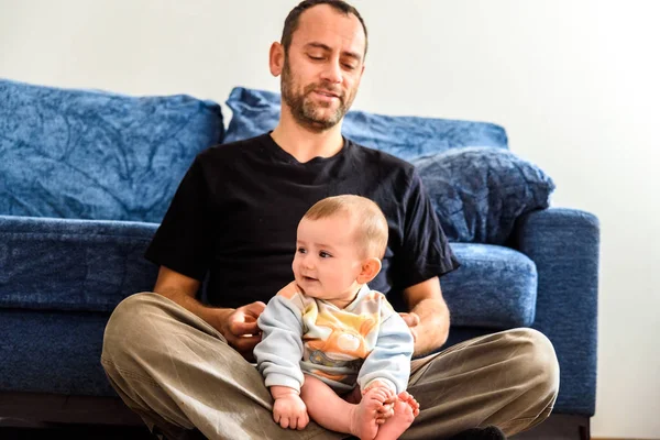 Funny baby sitting on his father's legs resting relaxed. — Stock Photo, Image