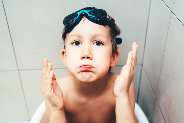 Portrait of boy in a bathtub with diving goggles putting funny f — Stock Photo, Image
