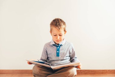 Isola dizlerinin üzerine bir kitap okuma ile katta oturan çocuk