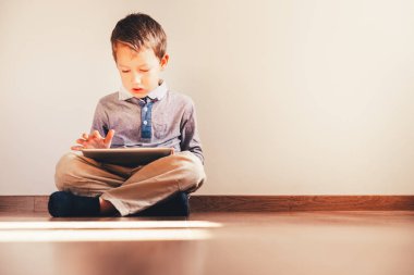 Onun elinde USI dijital tablet ile katta oturan çocuk