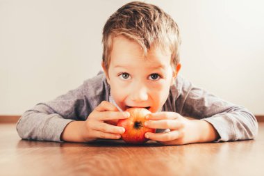 Bir elma ısırma aşağı yalan çocuk beyaz arka plan, konsantrasyon yalıtma