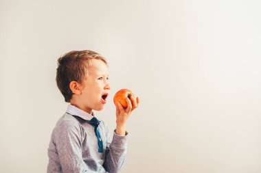 Bir elma yemek zorunda kızgın ve üzgün çocuk.