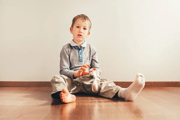 Niño con mucha independencia sentado en el suelo poniéndose —  Fotos de Stock