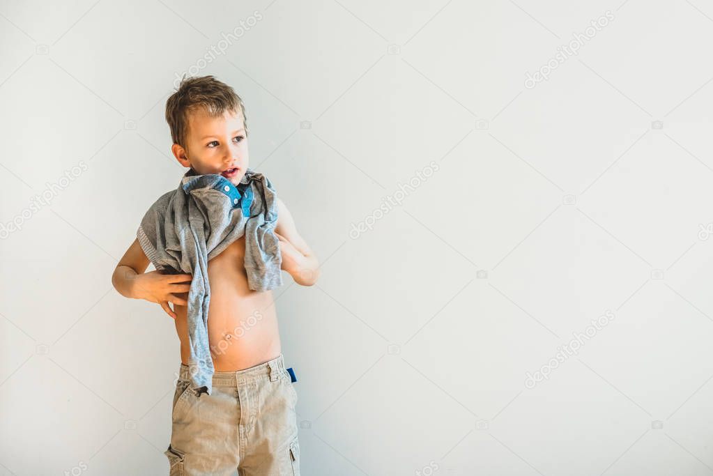 Child trying to take off his shirt and undress on his own.